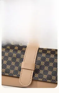 Close-up of brown leather wallet featuring gold clover pattern and khaki strap detail