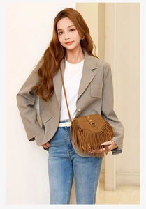 Sacoche en daim caramel avec franges portée avec un blazer gris et un pantalon en jean