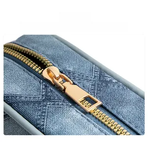 Macro shot of gold metal zipper on blue quilted denim crossbody bag with diamond stitching