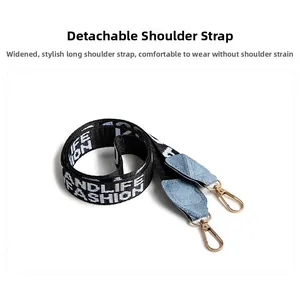 Detail showing wide detachable denim strap with gold hardware and fashion lettering