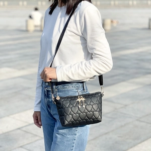 Fashionable black heart-quilted bucket bag with golden swan tassel and strap detail
