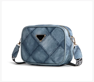 Detailed view of blue denim camera bag with diamond quilting and wide logo strap