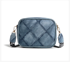 Detail of blue denim crossbody bag with quilted pattern and jacquard strap accents