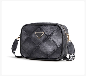 Close-up of denim texture crossbody bag with quilted pattern and gold triangular plaque