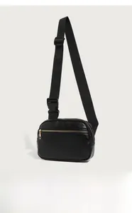 Detail of black pebbled leather waist bag with gold zippers and adjustable strap