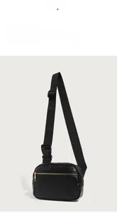 Detail view of brown pebbled leather crossbody bag with adjustable nylon strap and gold zippers