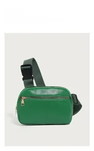 Detail of dark green lychee textured leather waist bag with gold zipper and adjustable strap