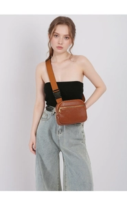 Detail of adjustable wide woven strap and buckle on brown lychee texture leather chest bag
