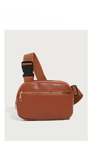 Close-up of brown textured leather chest bag with golden zipper and adjustable strap