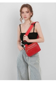 Detail of red pebbled leather chest bag featuring double gold zippers and wide strap