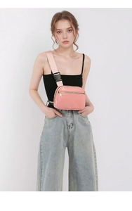Pink lychee grain leather chest bag with double zippers and wide fabric strap details