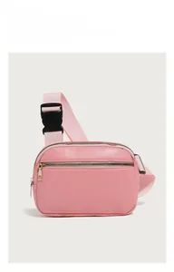 Detailed view of pink pebble grain PU leather chest bag with golden zippers and buckle
