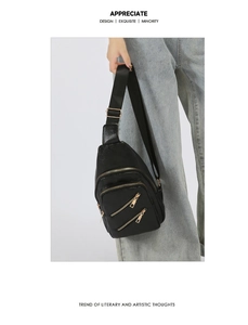 Détails d'un sac de poitrine en cuir noir avec zips dorés et bandoulière réglable