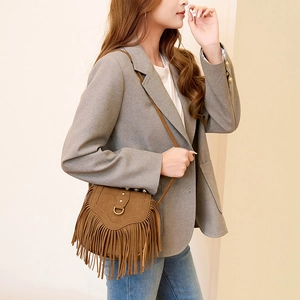 Sacoche vintage en daim marron avec franges et bandoulière portée par un mannequin