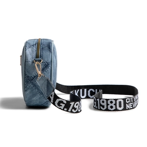 Blue denim crossbody camera bag with wide graphic strap and gold metal hardware