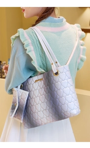 Detail of gradient heart-quilted tote bag with golden metal hardware on crossbody strap