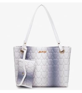 Detail of heart quilting on gradient purple tote bag with golden metal logo and mini pouch