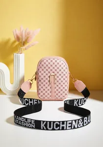 Close-up of pink mini crossbody phone bag with retro logo print and wide woven strap