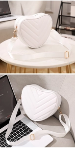 Lifestyle view of white heart-shaped crossbody bag with chevron quilting and gold hardware