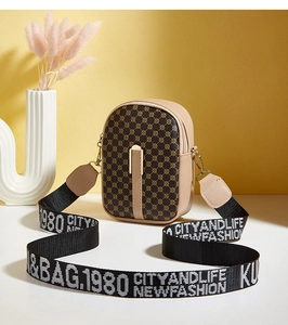 Detailed view of beige crossbody bag with geometric pattern and lettered woven strap