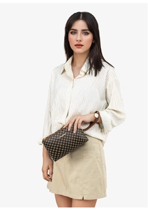 Close-up of vintage brown patterned crossbody bag held by a model in a minimal shirt