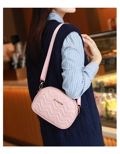 Détail du sac bandoulière matelassé rose avec broderie ondulée et logo doré