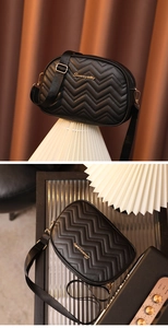 Détail du sac bandoulière noir avec matelassage en V, logo doré et sangle tissu
