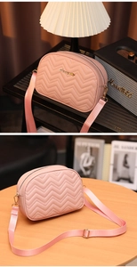 Vue détaillée du sac photo rose matelassé avec logo doré et bandoulière réglable