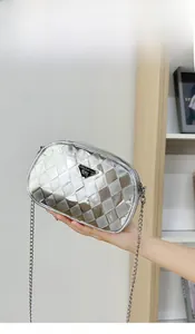 Vue détaillée d'un sac argenté matelassé avec logo métallique et bandoulière chaîne