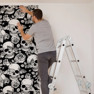 Gothic Halloween wallpaper with skulls, moths, and roses installed on a bedroom wall