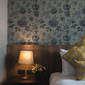 Modern nightstand lamp with fabric shade against blue floral wallpaper and wood panels