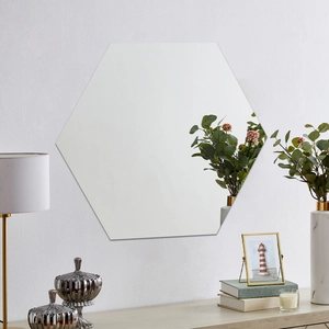 Modern frameless hexagonal mirror sticker reflecting green plants on a textured wall