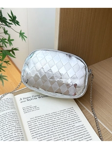 Détail du sac bandoulière argenté avec matelassage en losanges sur étagère bois