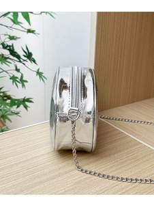 Détail du sac rond argenté métallisé avec surface réfléchissante et fermeture éclair
