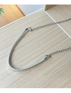 Détail d'une bandoulière en chaîne argentée avec épaulière en cuir et coutures précises