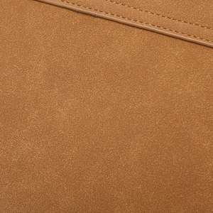 Dettaglio della texture scamosciata marrone e cuciture professionali su una borsa a busta