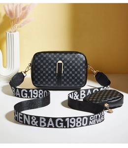 Detail of black patterned camera bag with a small coin purse on wide lettered strap