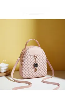 Detailed view of a pink PU leather mini crossbody bag with embossed patterns and cat charm
