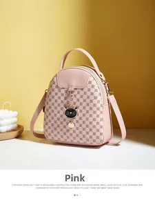 Detail of pink mini crossbody bag featuring geometric patterns and a cute cat pendant