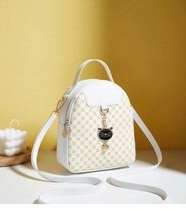 Detailed view of mini white and yellow crossbody bag with black cat metal charm
