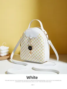 Detail of white mini crossbody bag with yellow geometric print and gold cat pendant charm