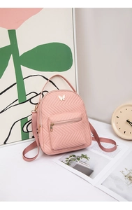Detailansicht eines rosa gesteppten Mini-Rucksacks mit Deko-Schmetterling und Gold-Zipper