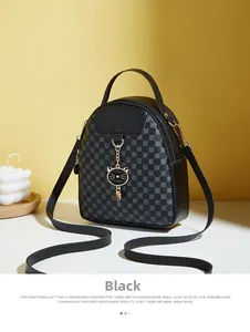 Detail of black mini crossbody bag with gold cat pendant and geometric quilting pattern