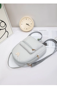 Detailansicht grauer gesteppter Mini-Rucksack mit Schmetterlingsdekor und Gurtband