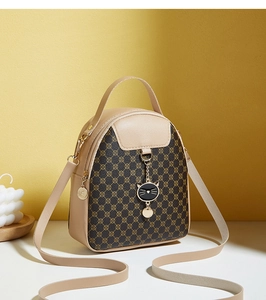 Detail of a beige and brown vintage pattern mini shoulder bag with a black cat charm