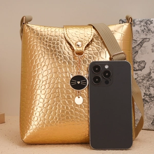 Détails du sac doré à motif crocodile avec pendentif chat et bandoulière tissée chic