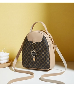 Detail of clover print mini bag with golden cat pendant against yellow wall background