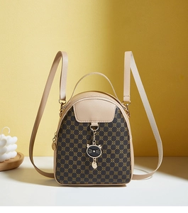 Close-up of vintage brown printed mini backpack with a metallic cat-shaped pendant