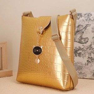 Détail du sac à main doré gaufré crocodile avec pendentif chat noir et bandoulière tissée