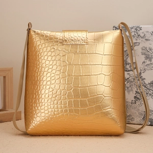 Détail du sac seau en similicuir doré avec motif crocodile et bandoulière en tissu tressé